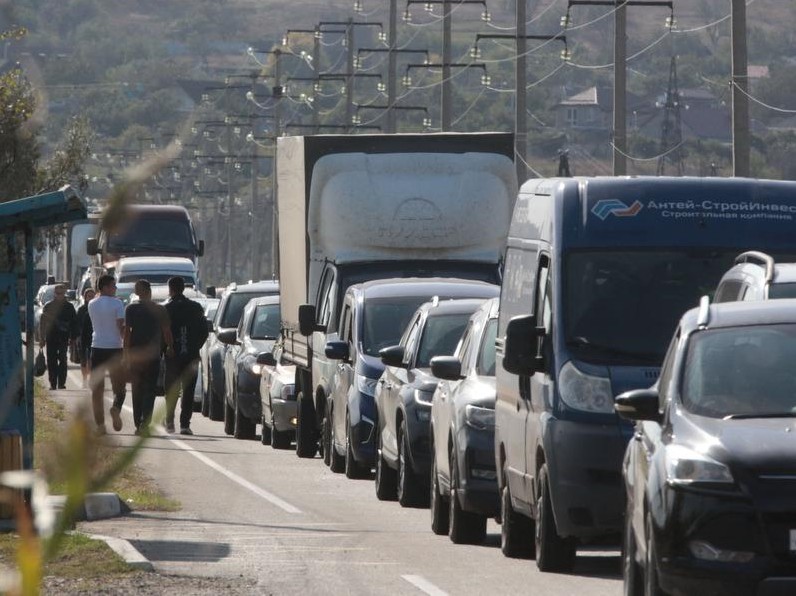 Pessoas esperam a balsa em seus carros depois que um caminhão explodiu e danificou fortemente a ponte Kerch que liga a Crimeia à Rússia, perto de Kerch — Foto: AFP