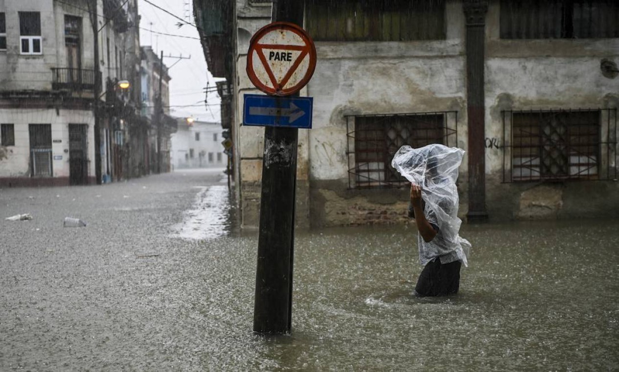 Homem caminha por uma rua inundada de Havana. O remanescente do furacão Agatha causou chuvas intensas e persistentes nas províncias ocidentais e centrais de Cuba — Foto: YAMIL LAGE / AFP