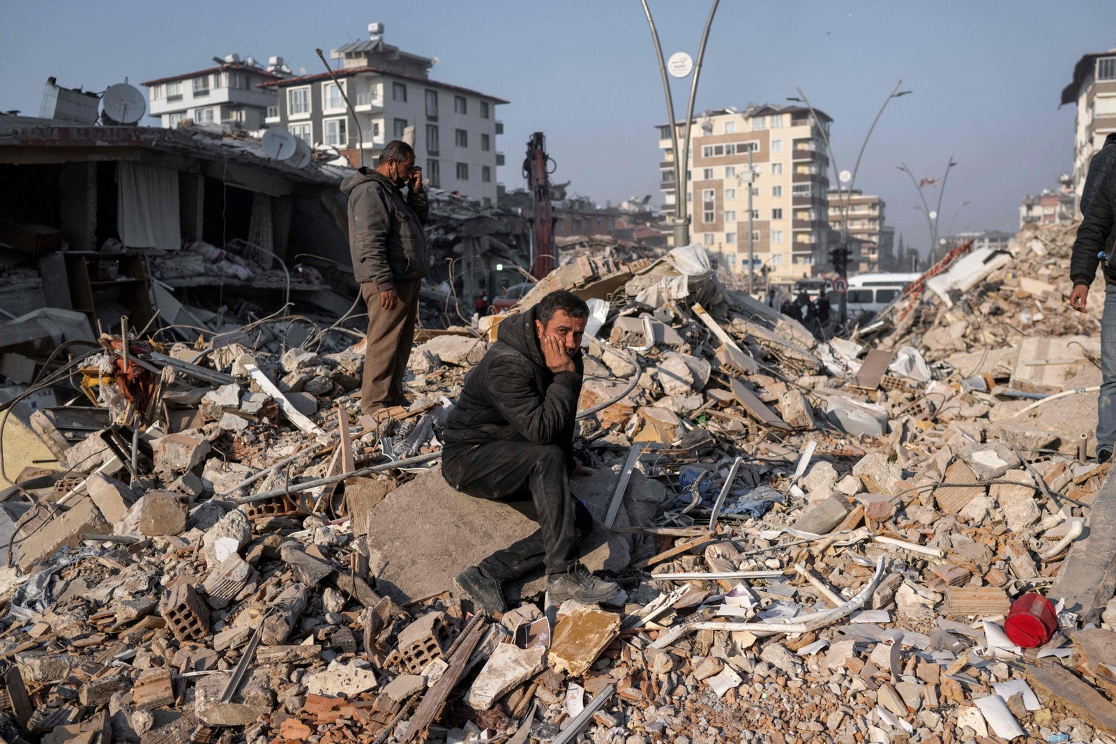 Homem se senta desolado sobre os escombros durante operações de resgate em Hatay, Turquia — Foto: BULENT KILIC/AFP