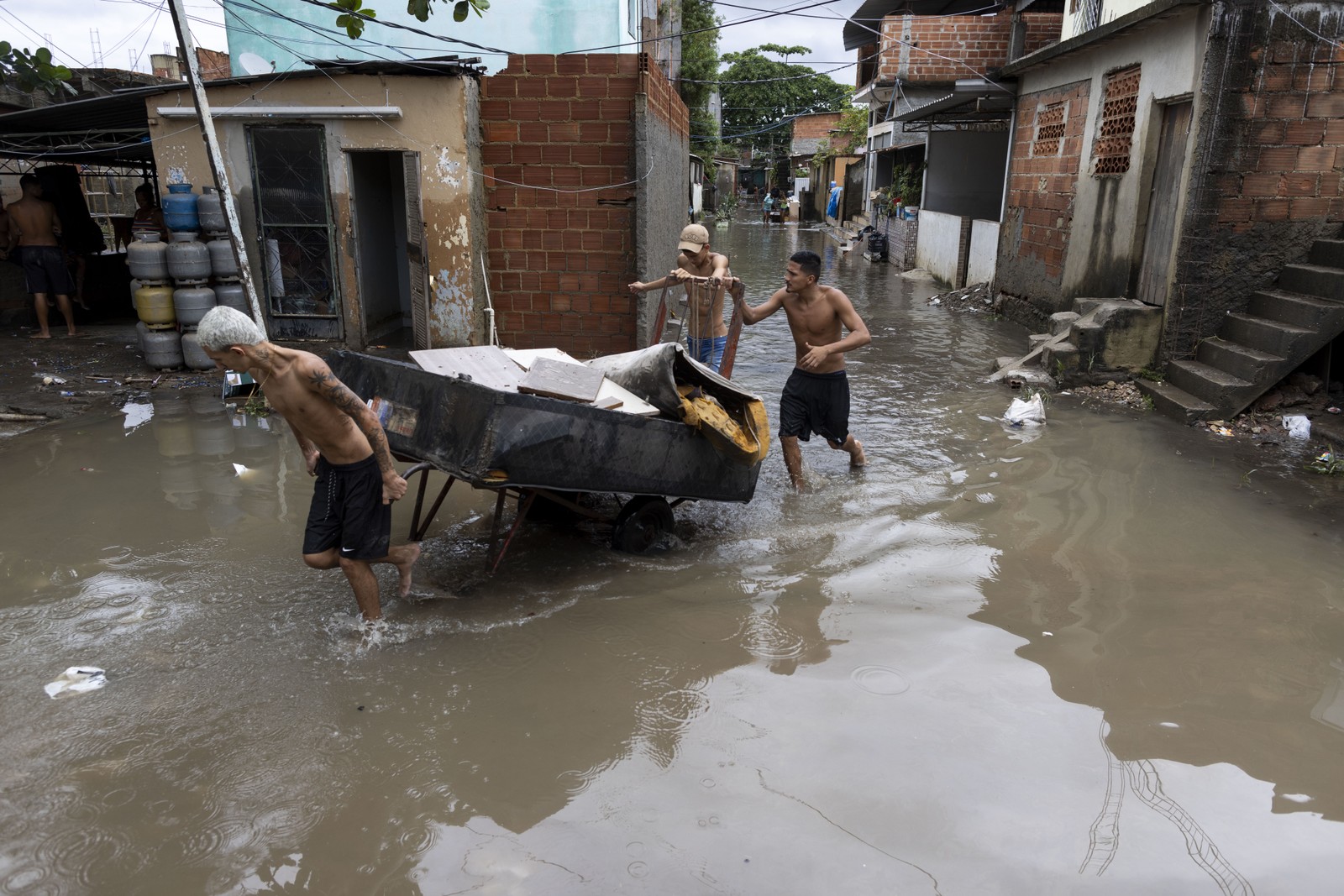 Moradores retiram móveis e objetos danificados com a chuva na comunidade Parmalat, em Acari. — Foto: Márcia Foletto