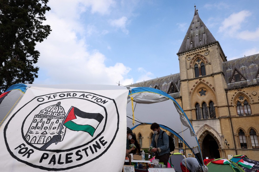 Apoiadores pró-palestinos se reúnem ao lado de uma faixa onde se lê “Oxford Action for Palestine” na Universidade de Oxford. — Foto: Adrian DENNIS / AFP