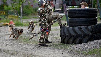 Meninos usam roupas camufladas e armas de plástico para emular guerra em brincadeiras — Foto: Sergei Supinsky/AFP