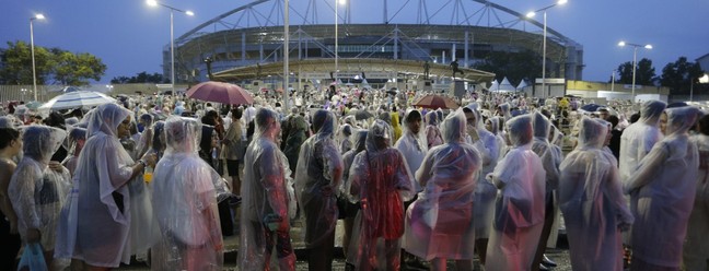 Sob chuva, fãs da cantora Taylor Swift aguardam para entrar no Estádio Nilton Santos — Foto: Domingos Peixoto / Agência O Globo