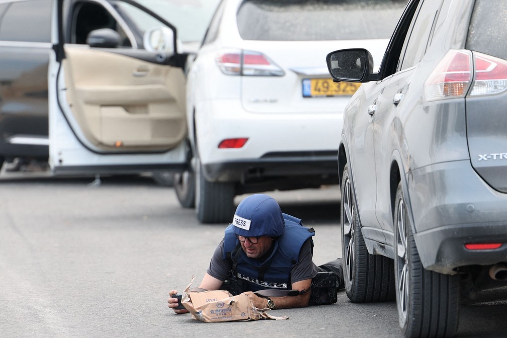 Um jornalista tenta se proteger em Sderot, durante um ataque com foguetes disparados na Faixa de Gaza — Foto: JACK GUEZ/AFP