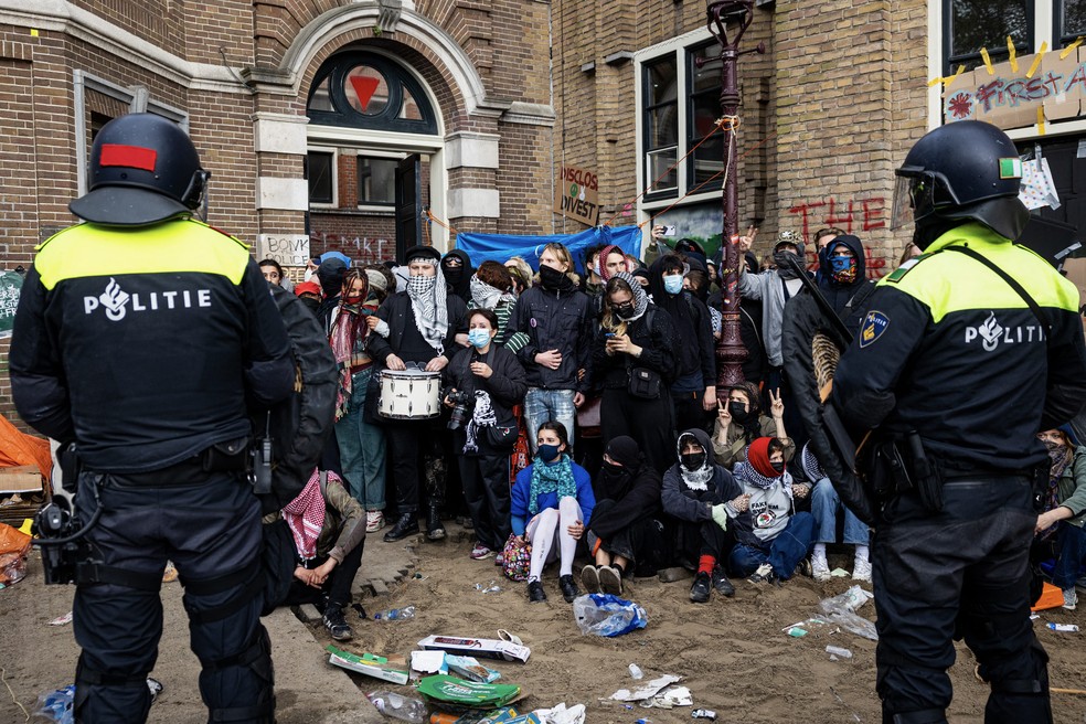 Policiais holandeses ficam em frente a estudantes pró-palestinos que ocupam a Universidade de Amsterdã (UvA). — Foto: RAMON VAN FLYMEN/AFP