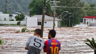 Pessoas observam uma rua inundada após fortes chuvas em Encantado, Rio Grande do Sul. Pelo menos dez pessoas morreram e 21 estão desaparecidas devido às fortes chuvas no estado. — Foto: Gustavo Ghisleni/AFP