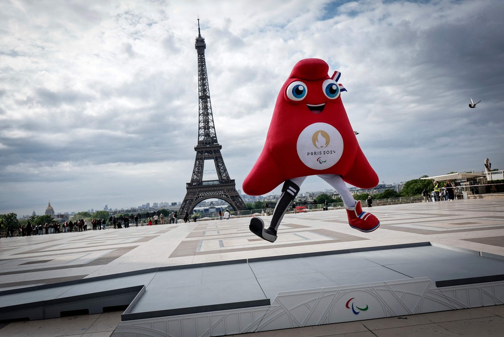 Phryge, a mascote oficial dos Jogos Paralímpicos de Paris 2024, salta no pódio colocado diante da Torre Eiffel — Foto: Stephane de Sakutin / AFP