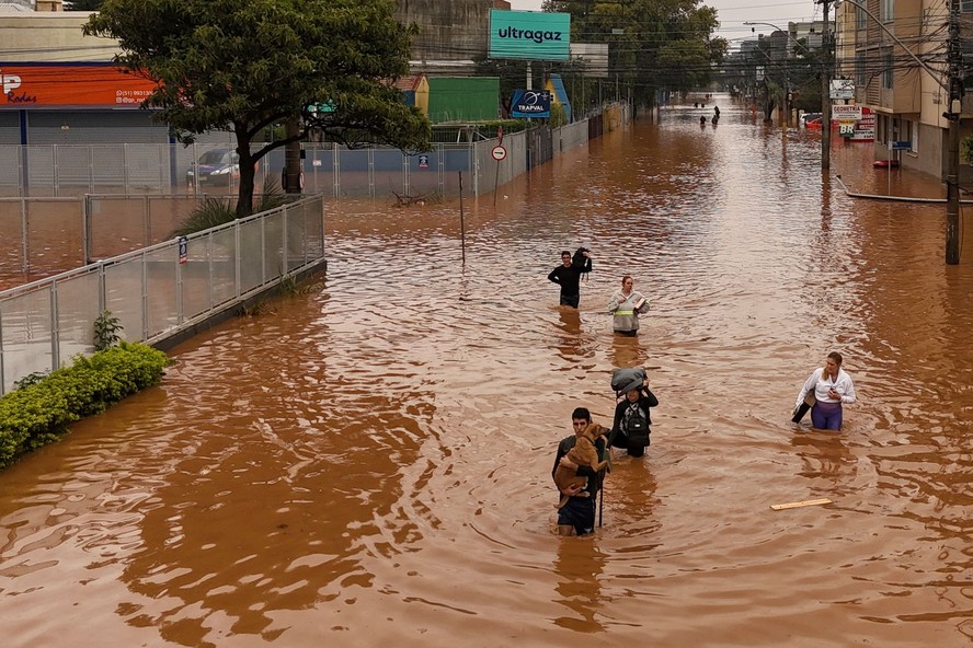 Chuvas no RS: pessoas tentam atravessar ruas alagadas no bairro Navegantes, em Porto Alegre