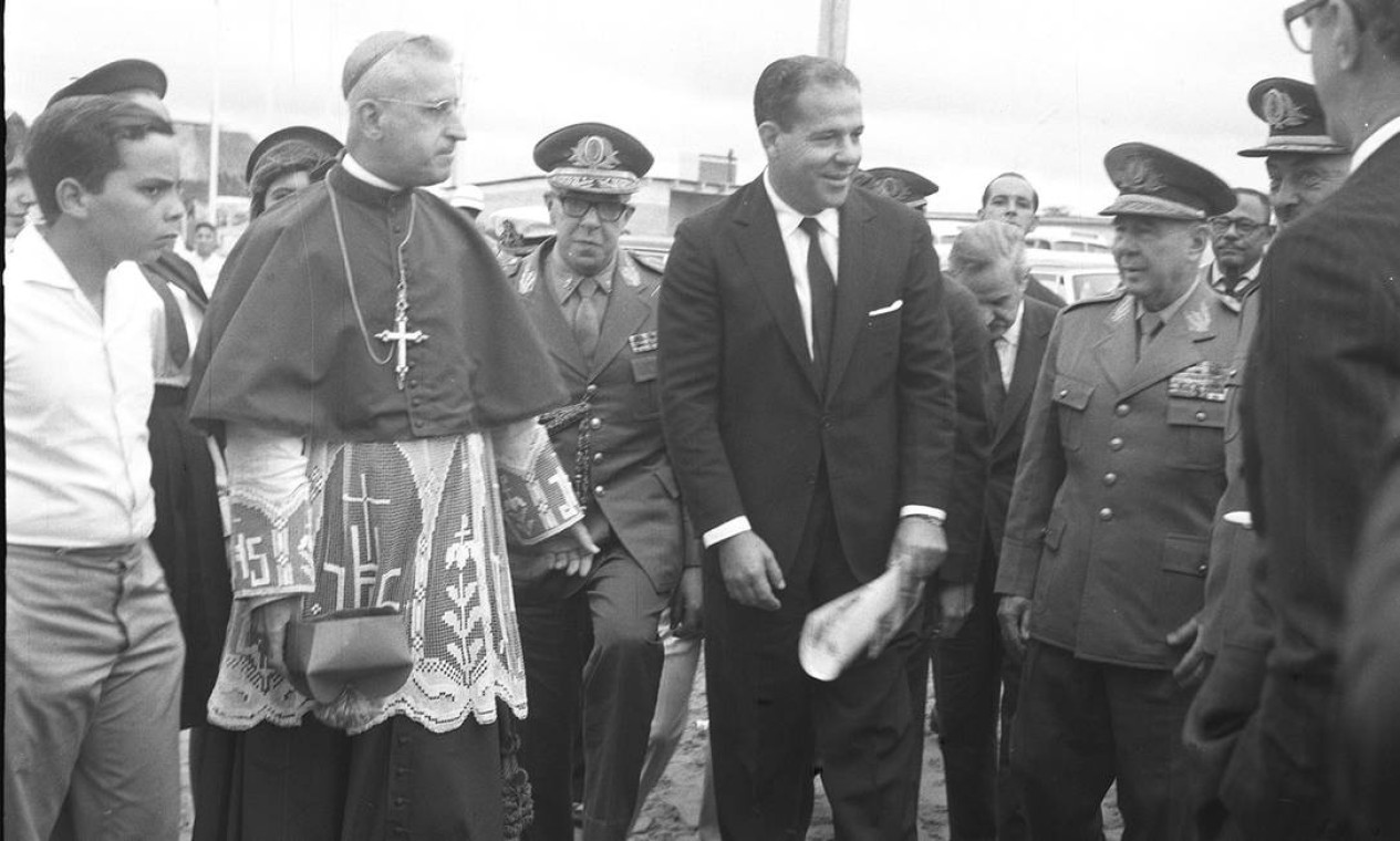 Em meados de 1961, Jango apresenta ao Congresso seu projeto de lei intitulado Reformas de Base. As propostas mexiam com setores conservadores, comandados pelas classes dominantes do país. Estavam inclusas as reformas agrária, bancária e urbana. Segundo o projeto, o governo autorizava a desapropriação de terras dos grandes latifundiários para redistribuí-las entre camponeses. Na foto, Jango e autoridades militares na Missa Campal que comemorou o 3º aniversário de Brasília — Foto: Arquivo