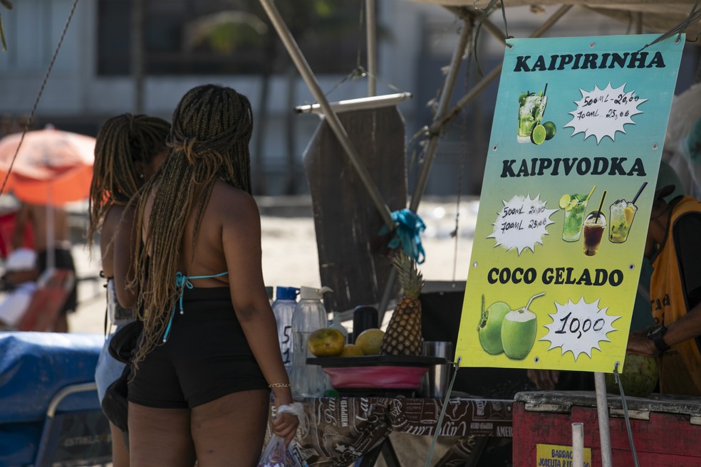 As mulheres observam a placa com os preços das mercadorias — Foto: Guito Moreto/Agência O Globo