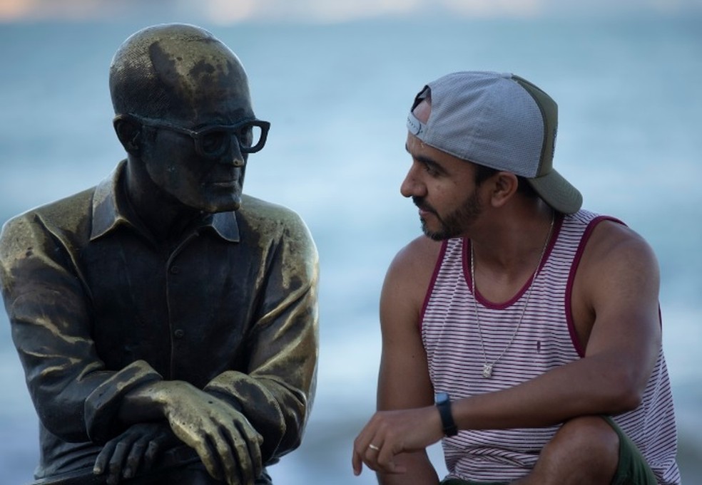 Estátua de Carlos Drummond, em Copacabana, é apreciada por turista — Foto: Alexandre Cassiano