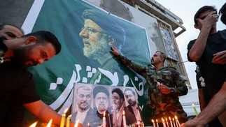 Iraquianos colocam flores e acendem velas para o falecido presidente do Irã, Ebrahim Raisi (foto), do lado de fora da embaixada iraniana em Bagdá — Foto: AHMAD AL-RUBAYE/AFP