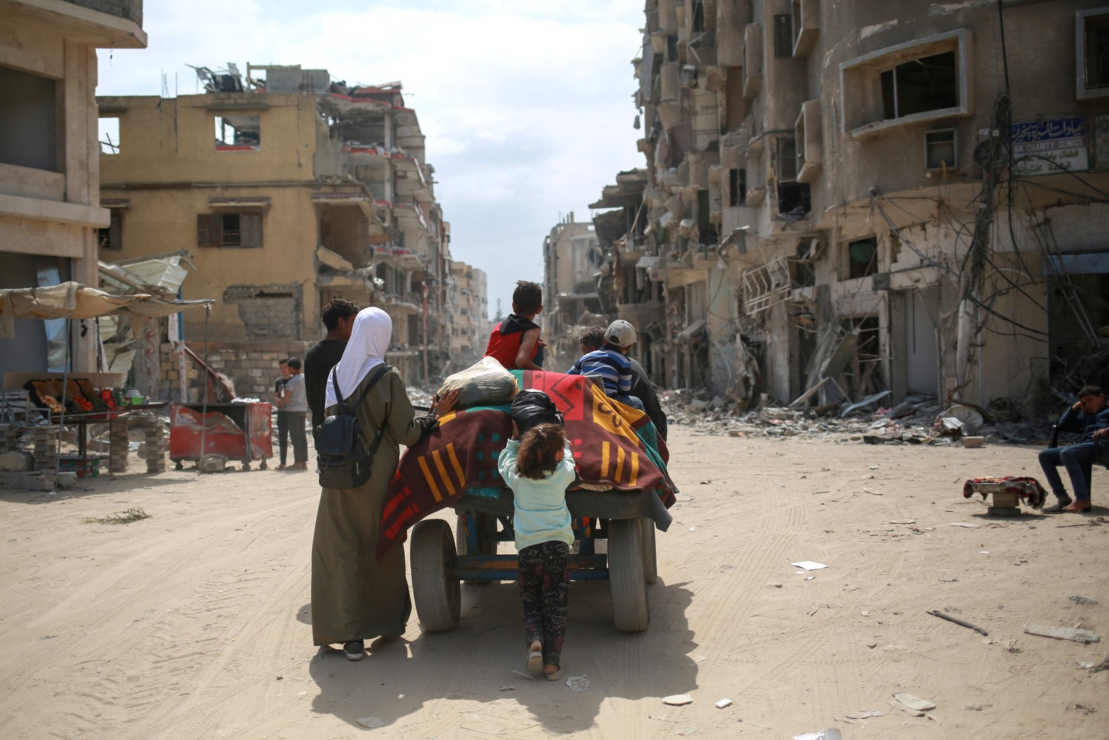 Palestinos transportam seus pertences em uma carroça em uma estrada repleta de edifícios danificados em Khan Yunis, no sul da Faixa de Gaza,  em meio ao conflito em curso entre Israel e o movimento Hamas. — Foto: AFP