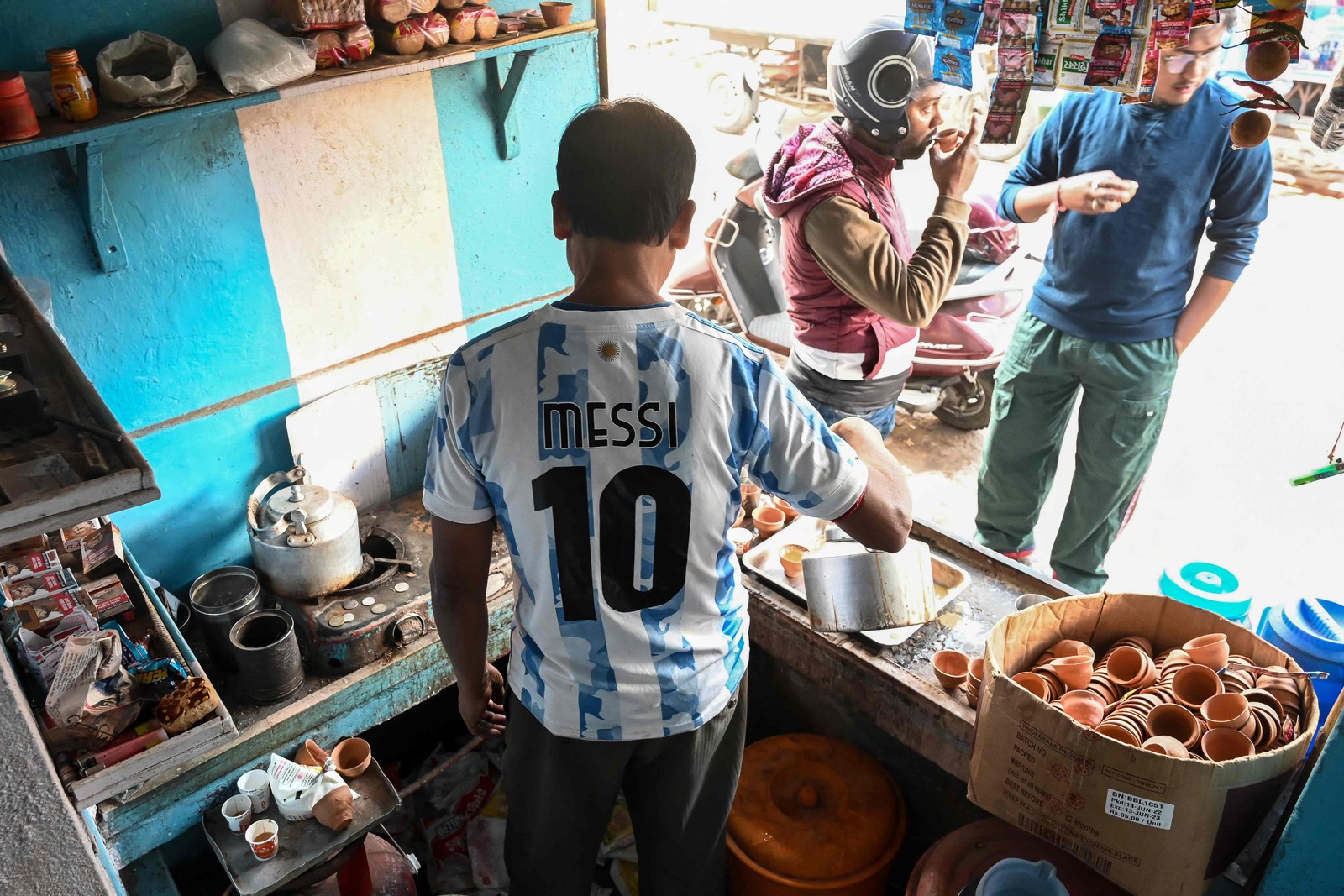 Dono de uma barraca de chá usa uma camisa da seleção da Argentina enquanto atende seus clientes em Ichhapur, a cerca de 35 km ao norte de Calcutá — Foto: DIBYANGSHU SARKAR / AFP