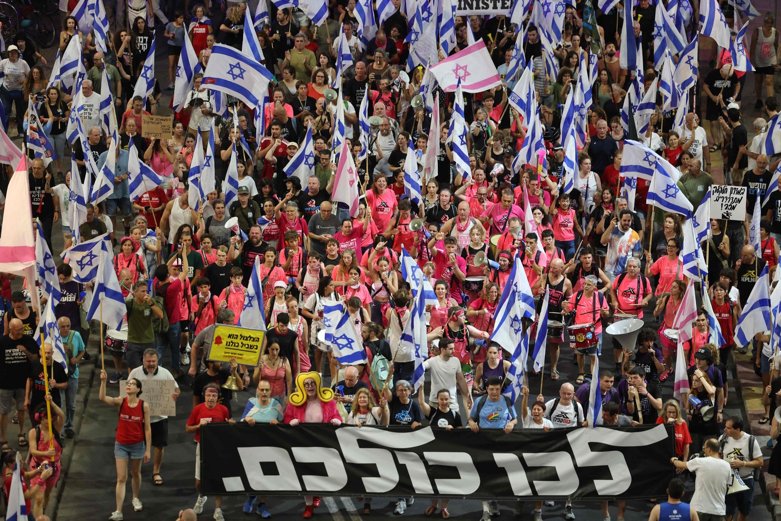 Manifestantes levantam bandeiras e faixas durante uma manifestação contra o plano de revisão judicial do governo israelense em Tel Aviv — Foto: Jack Guez/AFP