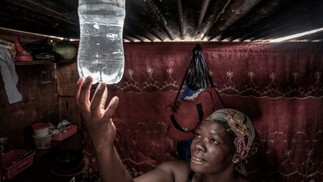 Garrafa d'água é usada improvisada como luminária em acampamento em Centurion, África do Sul, que enfrenta apões programados — Foto: AFP