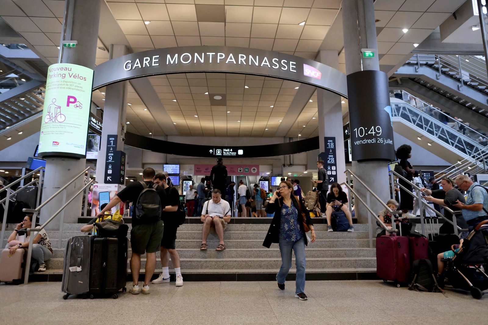 Passageiros aguardam informações sobre o horário de partida de trens na estação ferroviária Gare Montparnasse, em Paris, em 26 de julho de 2024, enquanto a rede ferroviária de alta velocidade da França foi atingida por atos maliciosos que interromperam o sistema de transporte horas antes da cerimônia de abertura dos Jogos Olímpicos de Paris 2024 — Foto: Thibaud MORITZ / AFP