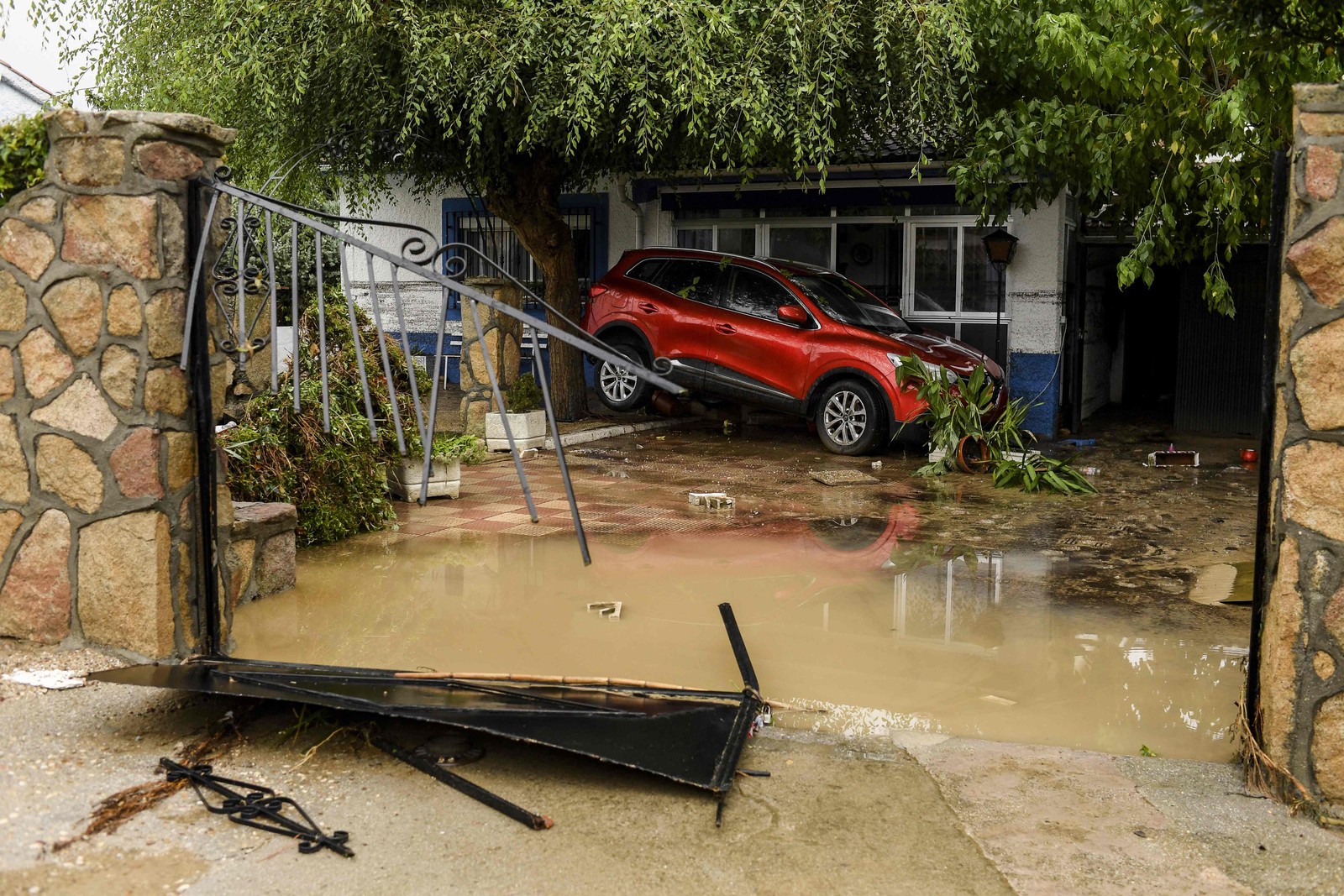 Carro preso em um jardim na cidade de Aldea del Fresno, na região de Madri — Foto: Oscar DEL POZO CAÑAS / AFP