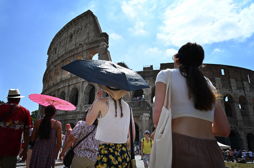 Turistas se protegem do sol com guarda-chuvas em Roma, durante onda de calor — Foto: Alberto PIZZOLI / AFP