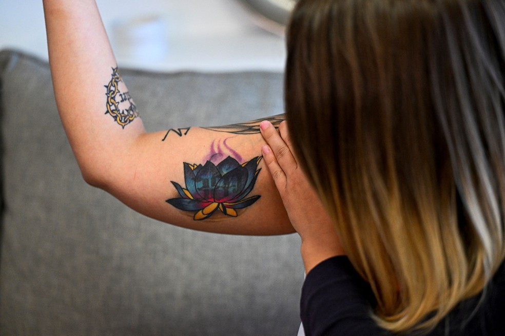 Breanna Cole, sobrevivente do tráfico sexual, mostra uma tatuagem de uma flor de lótus colorida feita no estúdio de Pinegar — Foto: Chandan Khanna / AFP