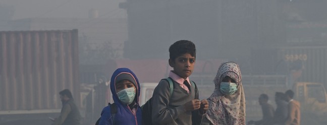 Crianças caminham para a escola em meio a fortes condições de poluição atmosférica em Lahore, Paquistão — Foto: ARIF ALI/AFP