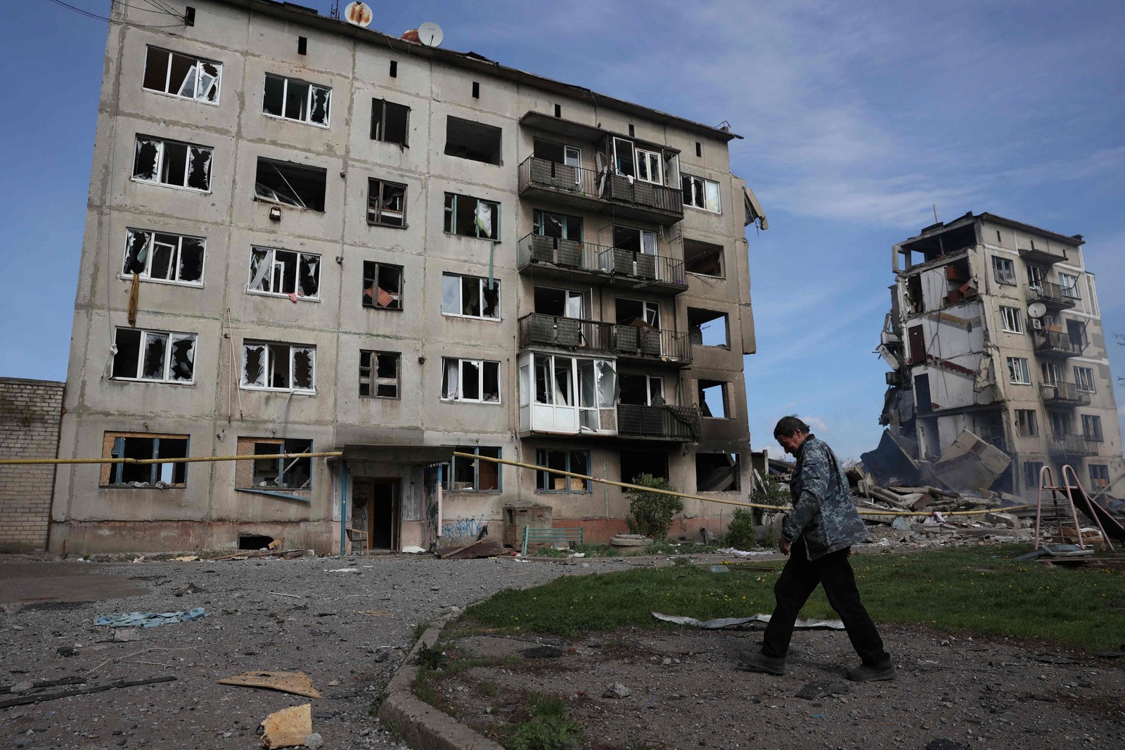 Um residente local passa por prédios de apartamentos destruídos por uma bomba aérea na vila de Ocheretyne, não muito longe da cidade de Avdiivka, na região de Donetsk,  em meio à invasão russa na Ucrânia. — Foto: Anatolii STEPANOV/AFP