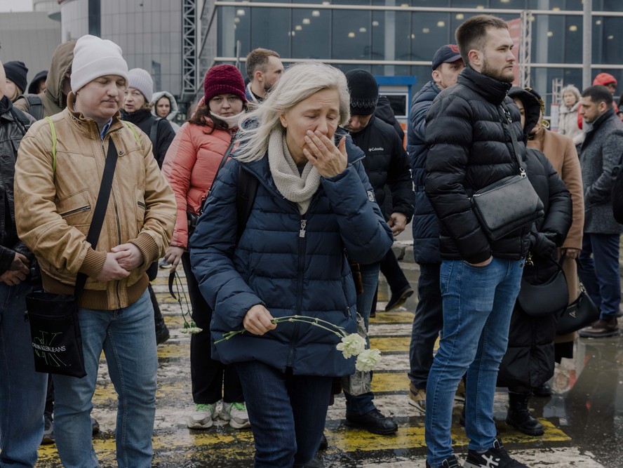 Pessoas levam flores para o Crocus City Hall, nos arredores de Moscou, depois do atentado de sexta-feira