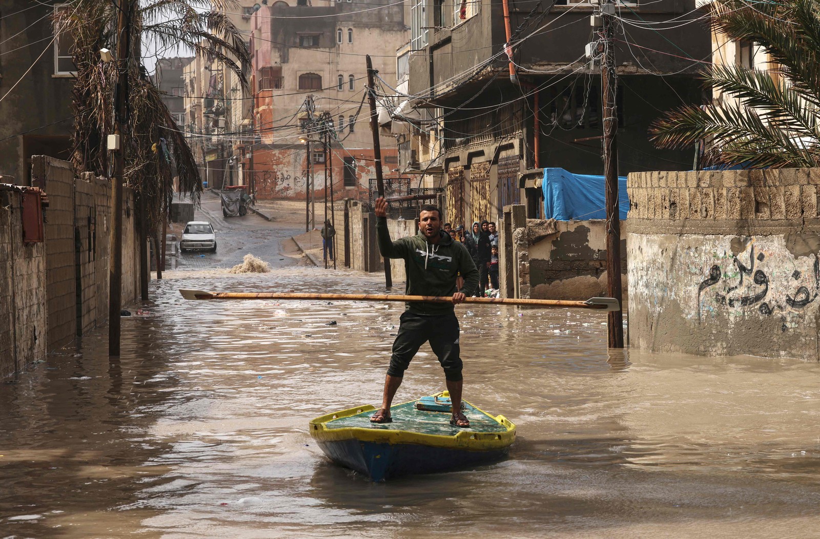 Palestino anda de prancha em uma rua inundada após fortes chuvas no campo de refugiados Al-Shati na Faixa de Gaza — Foto: MOHAMMED ABED/AFP