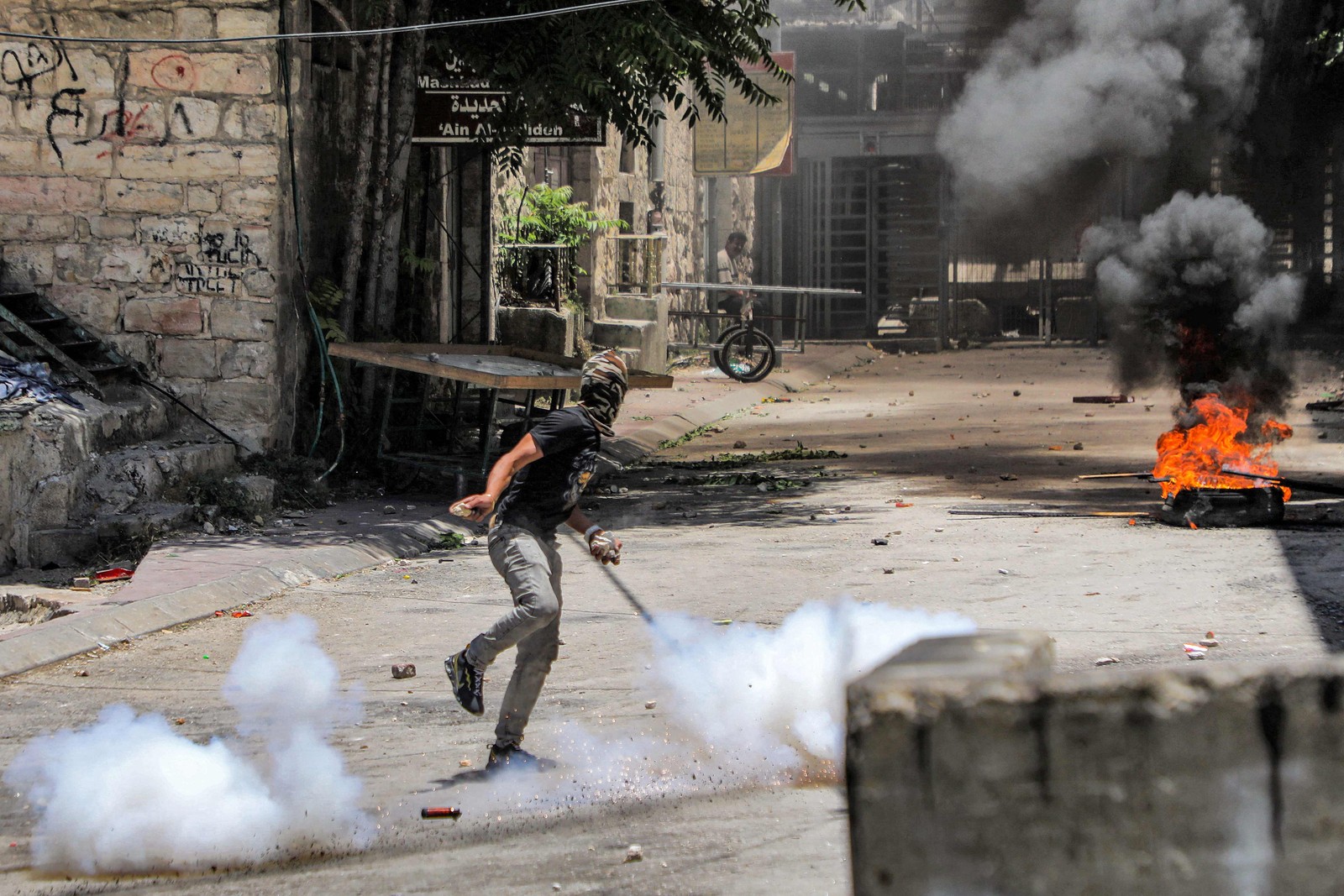 Manifestante palestino atira pedras durante confrontos com forças israelenses no centro de Hebron, em 4 de julho de 2023 — Foto: MOSAB SHAWER / AFP