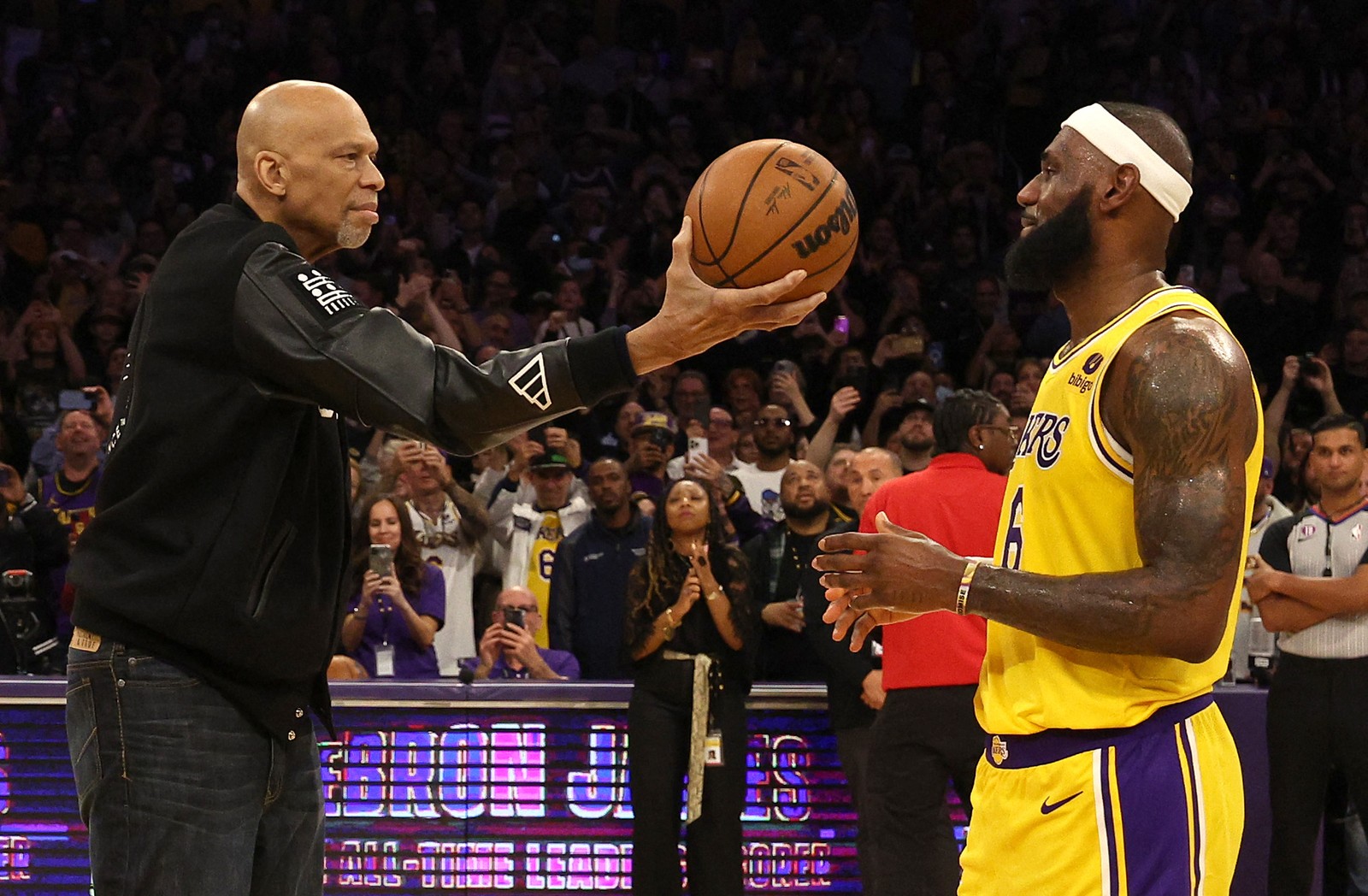 Kareem Abdul-Jabbar entrega cerimoniosamente a bola do jogo a LeBron James depois que este alcançou sua marca de pontos na NBA — Foto: Harry How / Getty Images via AFP