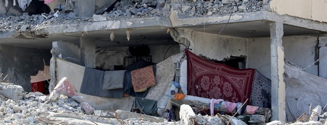 Situação humanitária em Rafah: um homem palestino e seus filhos sentam-se em uma sala destruída após o ataque aéreo israelense em Rafah, no sul da Faixa de Gaza — Foto: Eyad AL-BABA / AFP