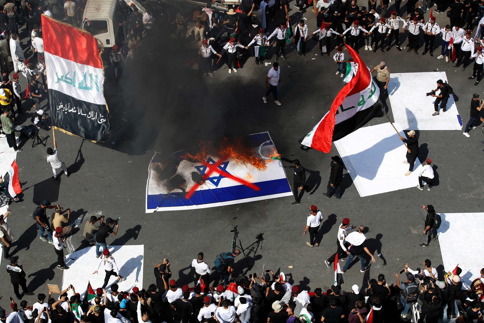 Manifestantes queimam uma bandeira israelense durante uma manifestação na Praça Tahrir, em Bagdá — Foto: Ahmad AL-RUBAYE/AFP
