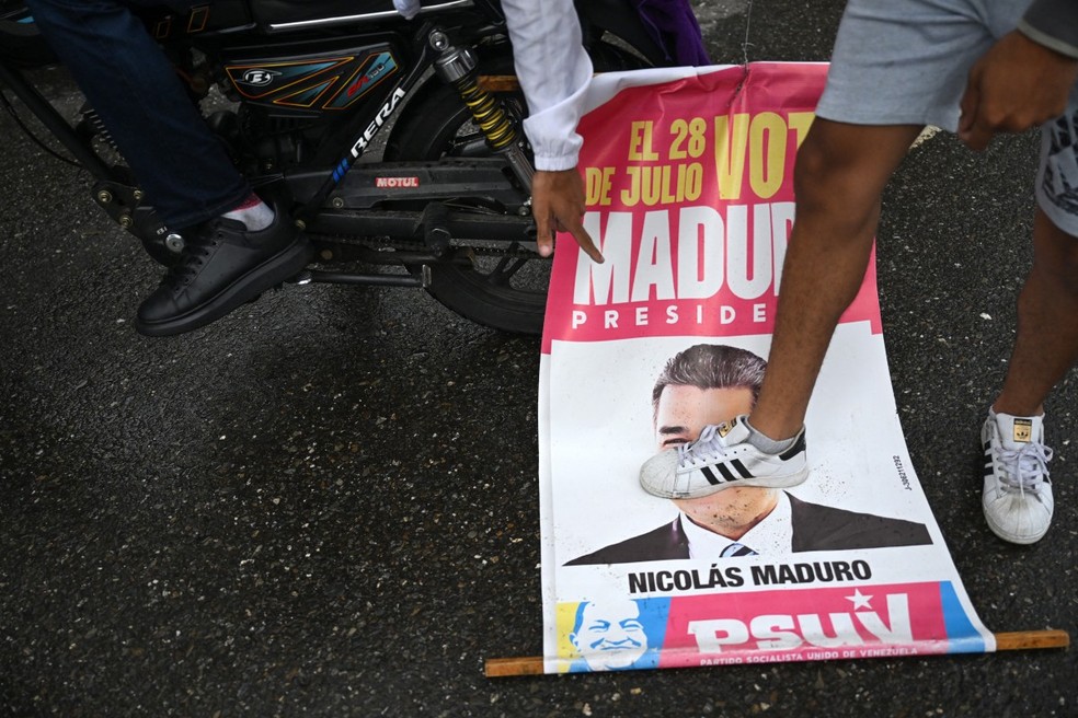 Oponente do governo do presidente venezuelano Nicolás Maduro pisa em um cartaz de campanha eleitoral com a imagem de Maduro durante um protesto no bairro de Petare — Foto: RAUL ARBOLEDA/AFP