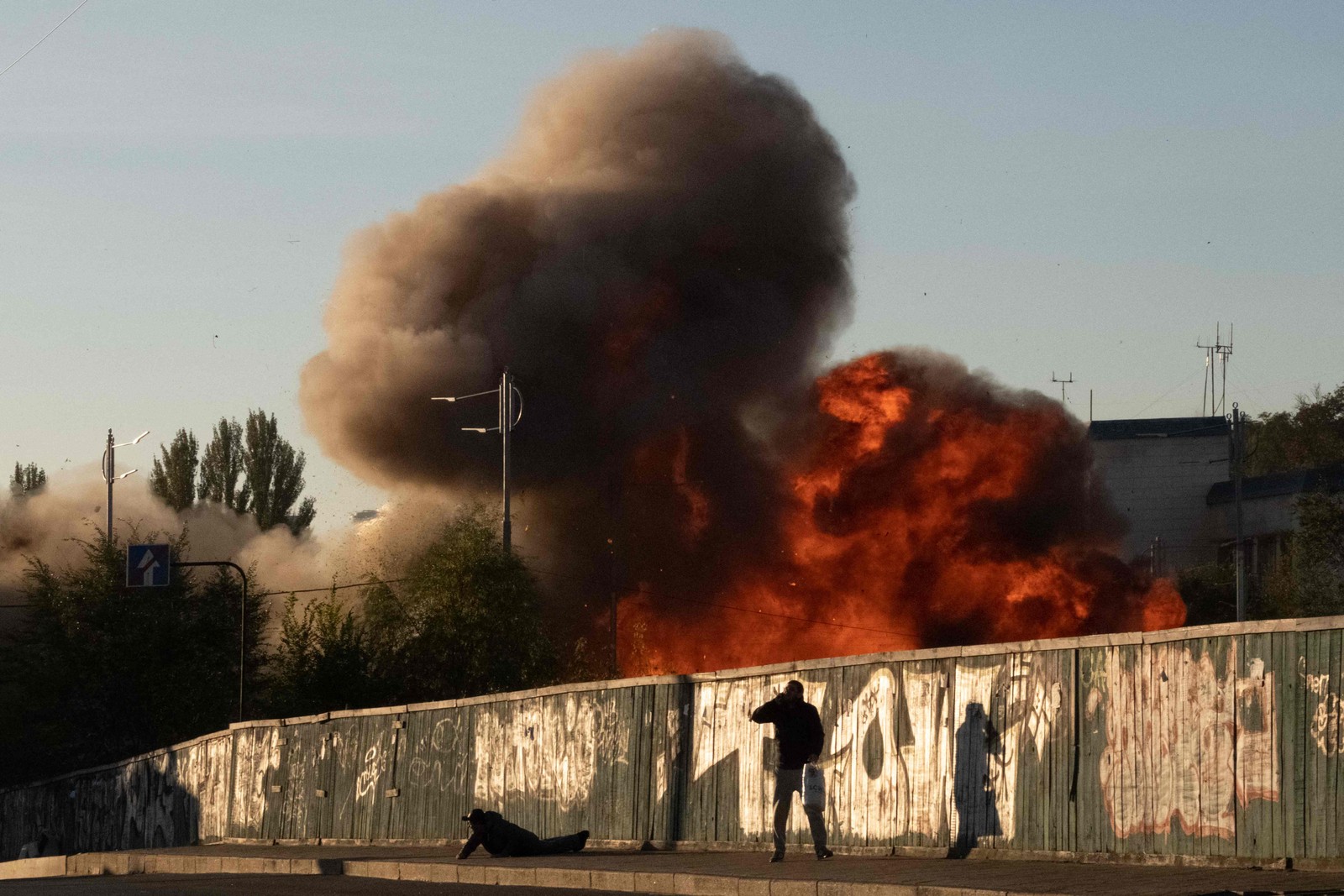 Homem cai no chão no momento de um ataque de drones russos em Kiev, na Ucrânia — Foto: Yasuyoshi CHIBA / AFP