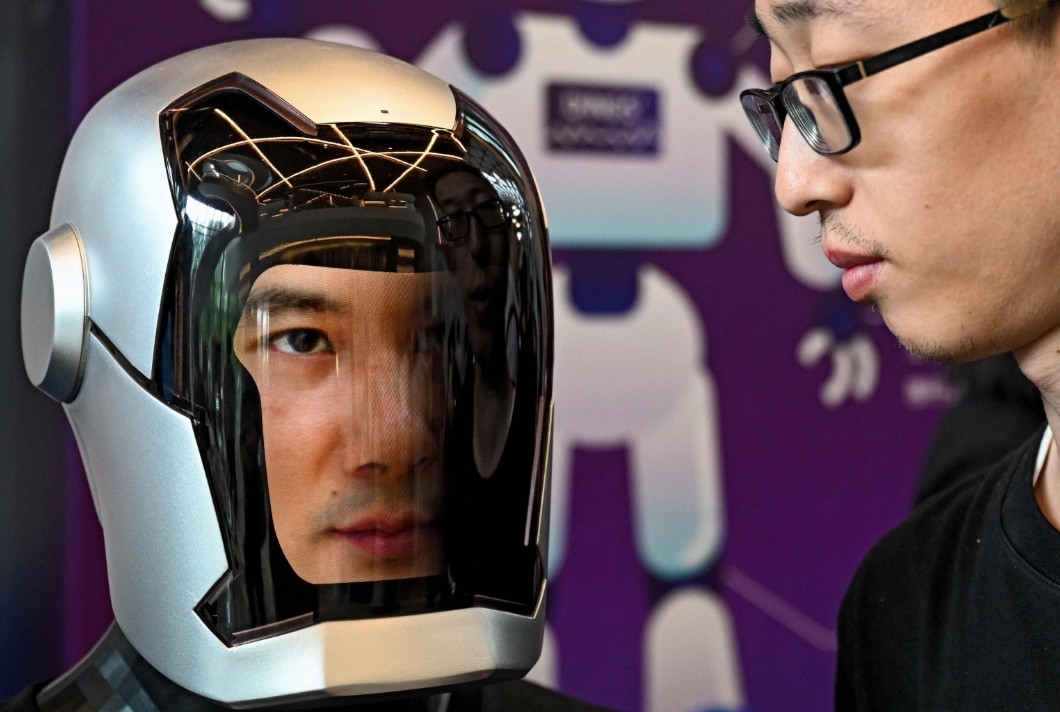 Um visitante olha bem de perto para um robô humanoide na Conferência de Desenvolvedores de Robôs Humanoides da China 2024, em Xangai — Foto: AFP