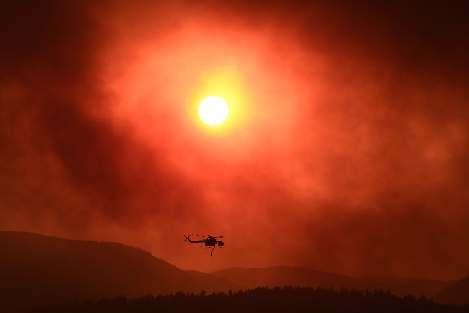Helicóptero sobrevoa área tomada por um incêndio florestal perto de Alexandrópolis, no norte da Grécia, em 21 de agosto de 2023. — Foto: Sakis MITROLIDIS / AFP