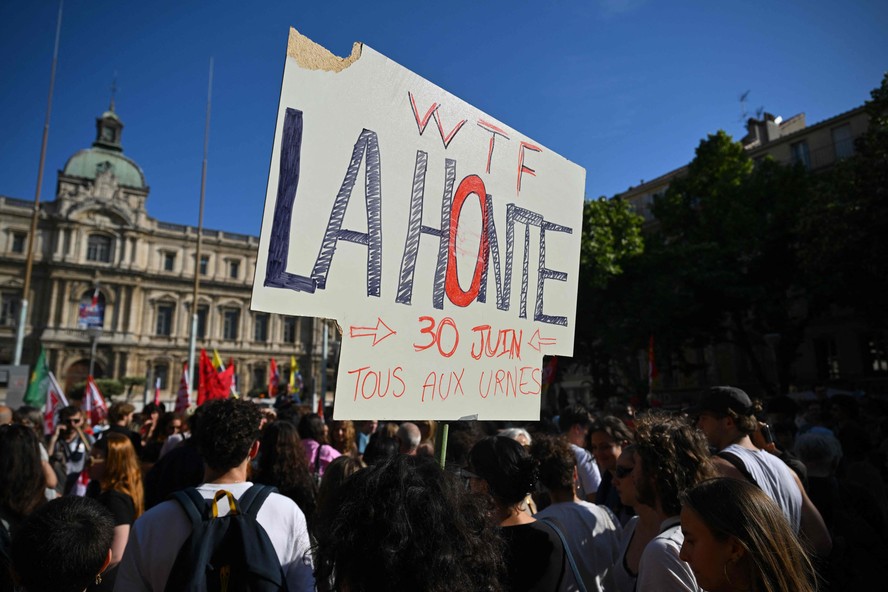 Um manifestante segura um cartaz que diz 'Vergonha! Todos às urnas em 30 de junho' durante uma manifestação contra o partido francês de extrema direita 'Rassemblement National' (RN) em Marselha, sul da França.