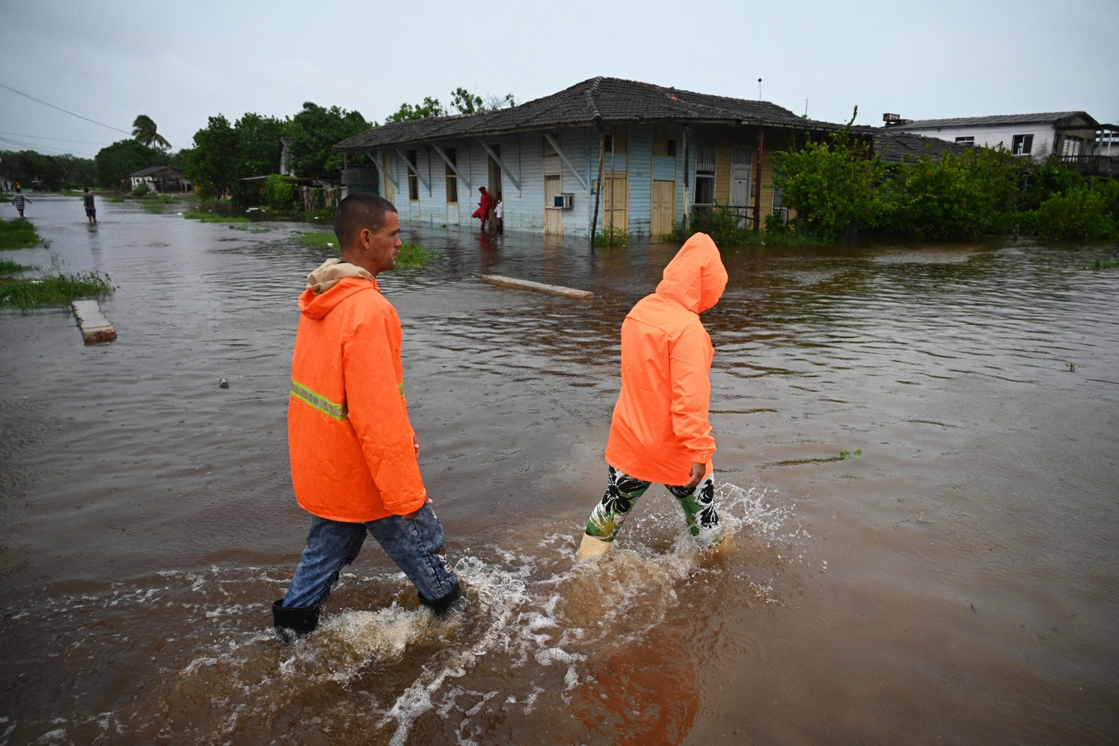 Pessoas caminham por uma rua inundada em Batabano, província de Mayabeque (Cuba), durante a passagem da tempestade tropical Idalia. — Foto: Yamil LAGE / AFP