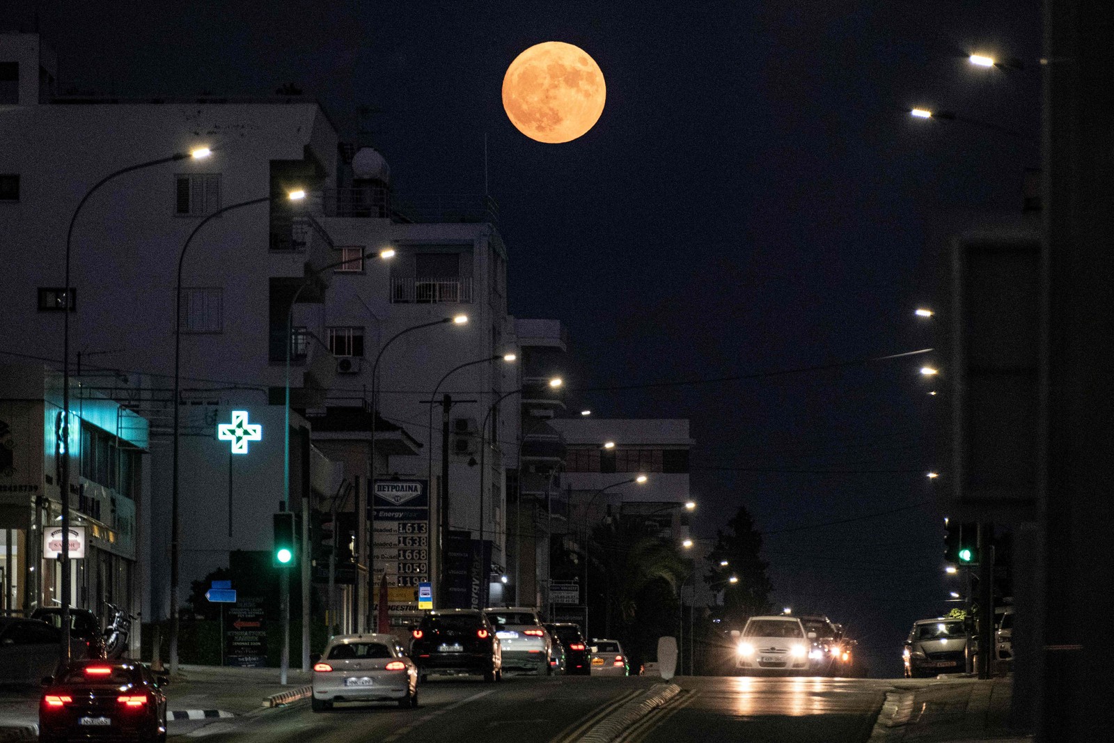 A "Superlua Azul" surge acima dos veículos ao longo de uma rua em Nicósia no Chipre — Foto: Amir MAKAR / AFP