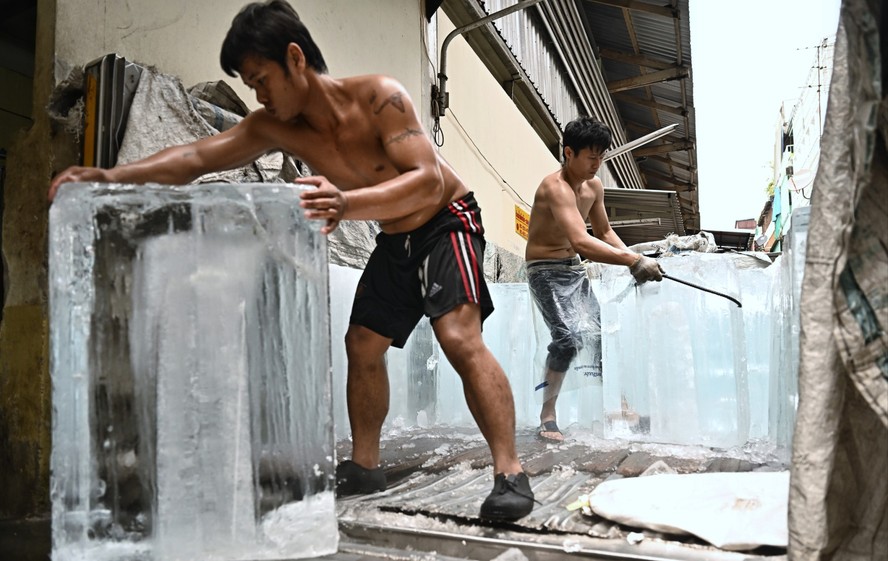 Trabalhadores movem blocos de gelo para uma unidade de armazenamento em um mercado de produtos frescos durante as ondas de calor em Bangkok, Tailândia