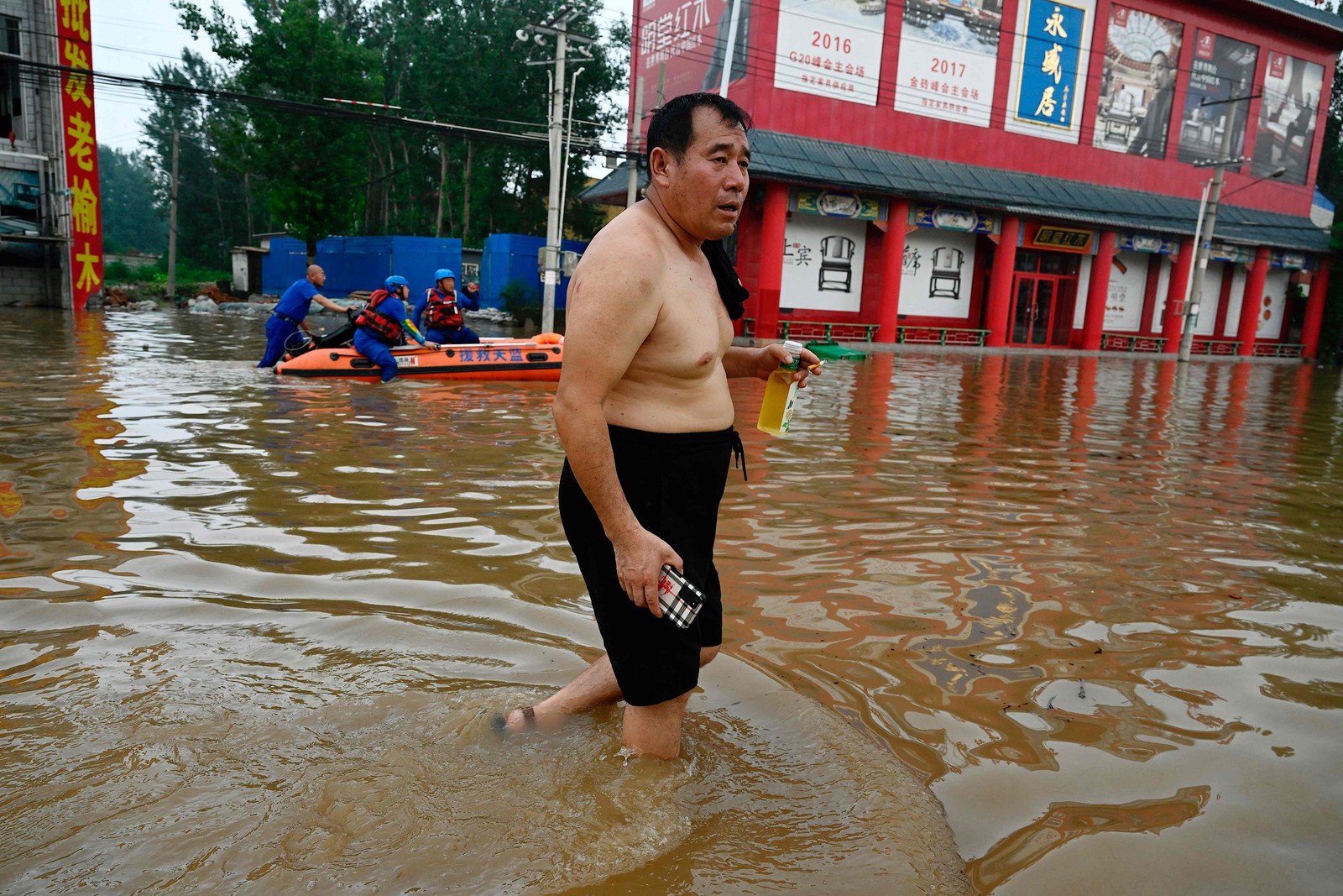 Homem caminha por rua inundada após fortes chuvas em Zhuozhou, na província de Hebei, no norte da China, em 2 de agosto de 2023 — Foto: Jade Gao / AFP