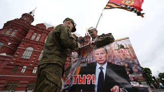 Ativista segura cartaz com imagem de Vladimir Putin na Praça Vermelha; presidente russo prometeu punir mercenários rebeldes — Foto: Natalia KOLESNIKOVA / AFP