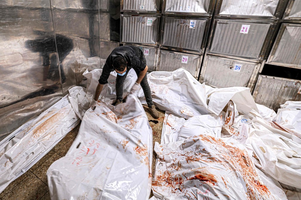 Um funcionário do necrotério arruma sacos para cadáveres no hospital al-Shifa na cidade de Gaza — Foto: Mahmud HAMS/AFP