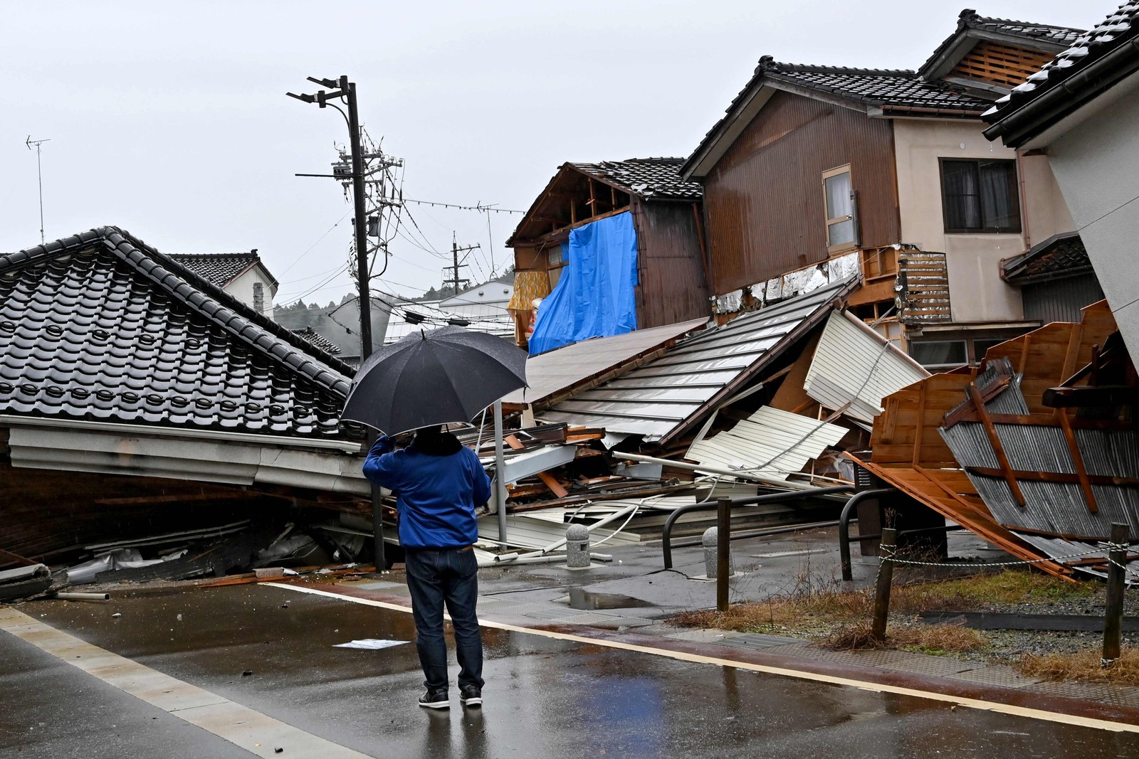 Fortes chuvas e ruas bloqueadas pelos escombros de casas dificultaram as ações de resgate no Japão — Foto: KAZUHIRO NOGI/AFP
