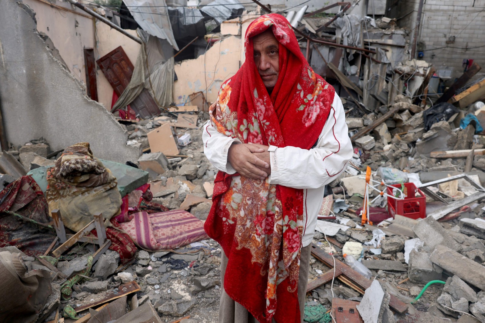 Um palestino coberto com um cobertor está nos escombros de uma casa após o bombardeio israelense ao campo de refugiados de Rafa, no sul da Faixa de Gaza, em 15 de novembro de 2023 — Foto: Mohammed ABED / AFP