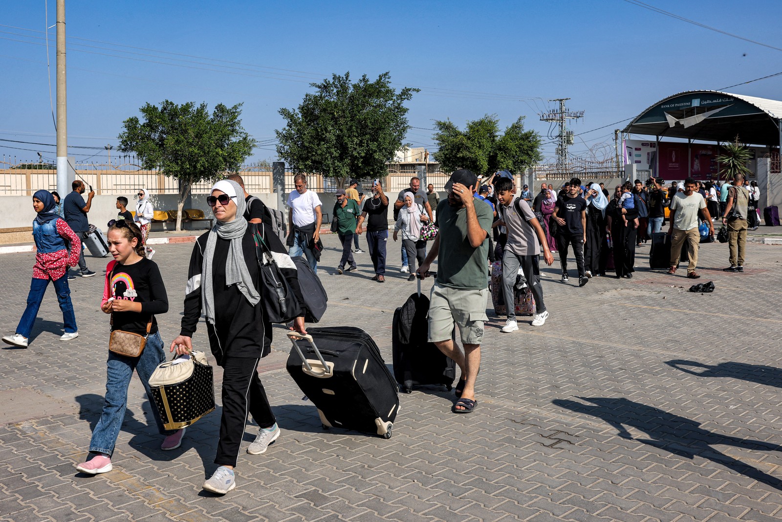 Pessoas entram na passagem de fronteira de Rafah, no sul da Faixa de Gaza, antes de cruzarem para o Egito — Foto: Mohammed ABED/AFP