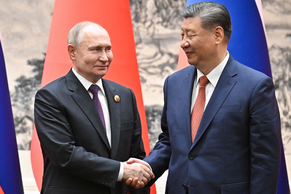 Putin e Xi se entreolham enquanto posam para foto em Pequim — Foto: Sergei Bobylyov/AFP