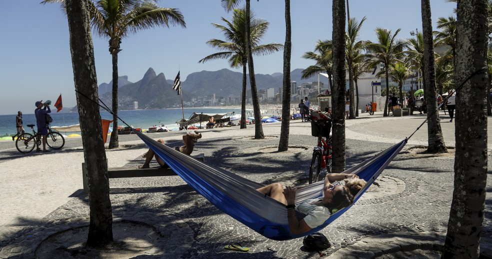 Fotógrafa pendurou uma rede na sombra para se proteger do sol na praia — Foto: Gabriel de Paiva/Agência O Globo