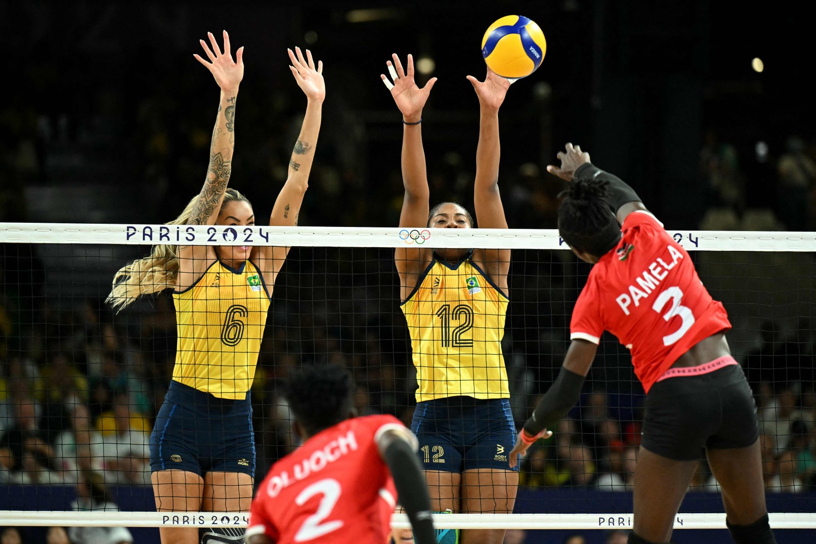 Thaisa Daher De Menezes e Ana Cristina Menezes Oliveira De Souza saltam para bloquear a bola da queniana Pamella Adhiambo Owino durante a partida de vôlei feminino da fase preliminar entre Brasil e Quênia — Foto: Natalia KOLESNIKOVA / AFP