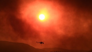 Helicóptero sobrevoa área tomada por um incêndio florestal perto de Alexandrópolis, no norte da Grécia, em 21 de agosto de 2023. — Foto: Sakis MITROLIDIS / AFP